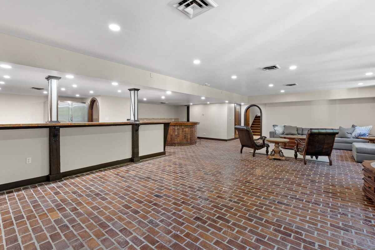 Basement recreation room with brick flooring, a bar, and seating area.