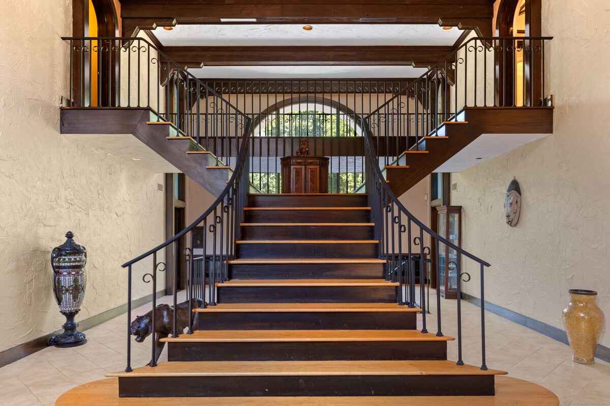 Grand staircase with ornate metal railings in a large entryway.