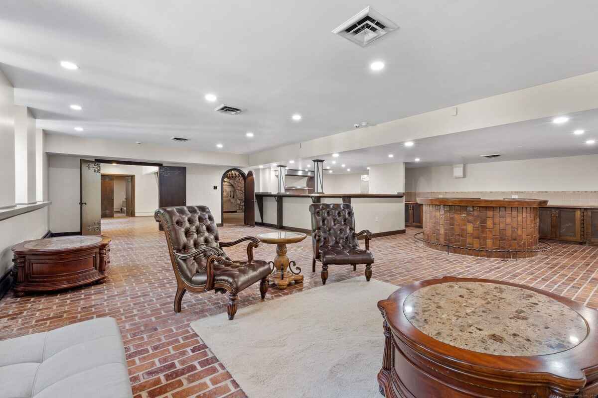 Basement game room with brick flooring, a bar, and comfortable seating.