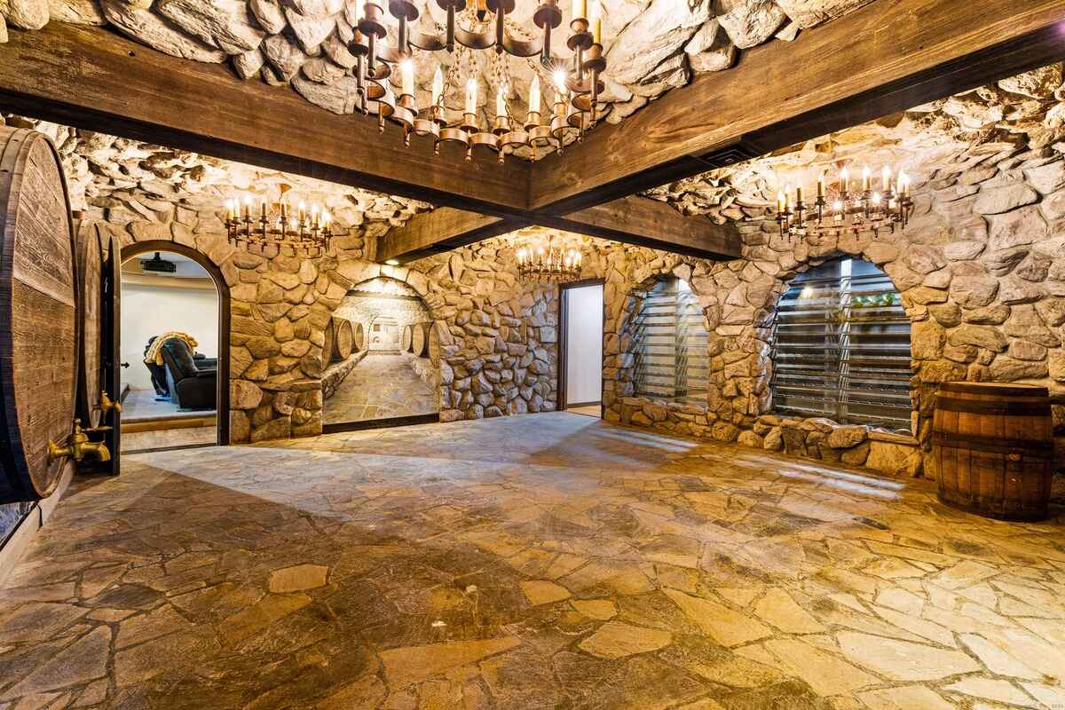 Wine cellar with stone walls, wood beams, and multiple chandeliers.