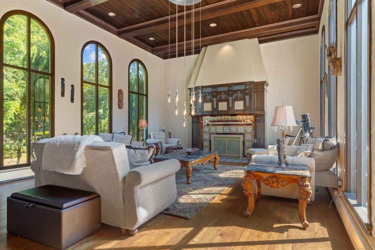 Living room with arched windows, hardwood floors, and a large fireplace.