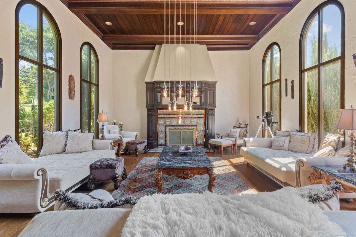 Living room with high ceilings, arched windows, a fireplace, and ornate furniture.