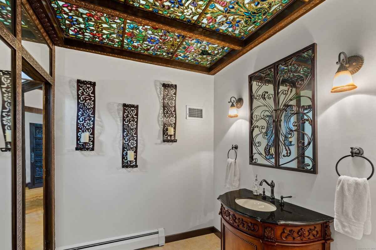 Bathroom with a stained-glass ceiling, ornate mirror, and dark wood vanity.