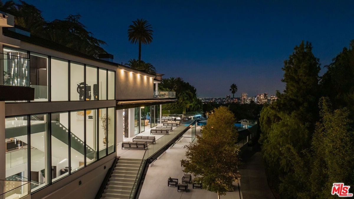 Bathed in the soft glow of twilight, the residence commands attention with its dramatic lines and expansive glass facade. The infinity pool appears to merge with the city lights below, creating a breathtaking spectacle of urban and natural beauty.