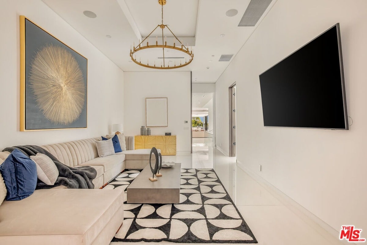 Clean lines and a neutral color palette define the aesthetic of this open-plan living area, where natural light enhances the sense of spaciousness. The large sectional sofa and statement artwork create a comfortable and inviting atmosphere, perfect for relaxation and entertaining.