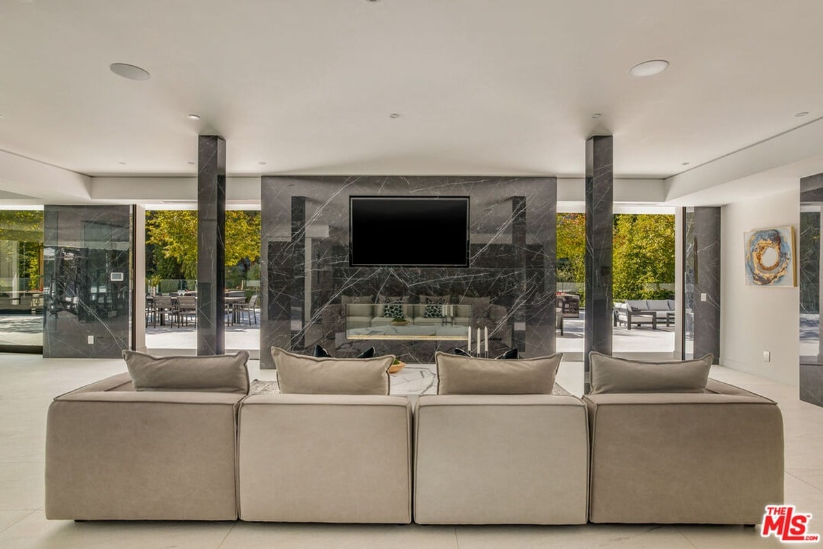 Floor-to-ceiling windows showcasing breathtaking city views are the undeniable centerpiece of this luxurious living room. The curved sectional sofa and elegant chandelier complement the panoramic vista, creating a sophisticated and inviting atmosphere perfect for relaxation and entertaining.