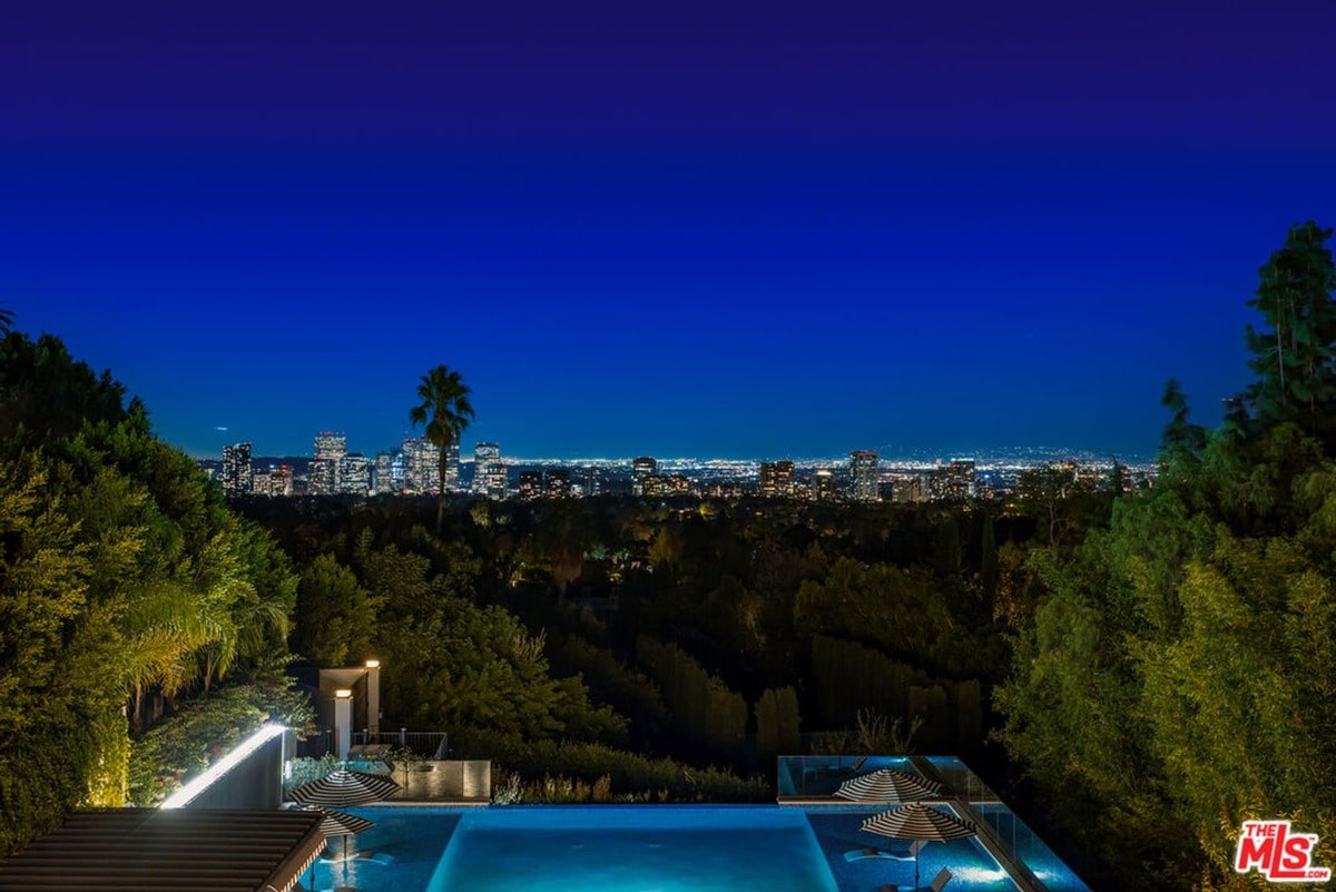 An infinity pool, seemingly suspended in air, frames a breathtaking panorama of city lights twinkling on the horizon. This luxurious retreat offers an unparalleled view, seamlessly blending indoor opulence with the awe-inspiring beauty of the night sky.