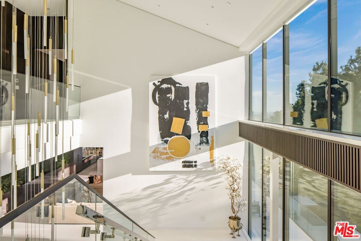 A dramatic, abstract artwork serves as a focal point in this light-filled atrium, its bold colors and shapes contrasting with the clean lines of the modern architecture. Floor-to-ceiling windows offer a stunning view of the surrounding landscape, blurring the lines between indoor and outdoor spaces.