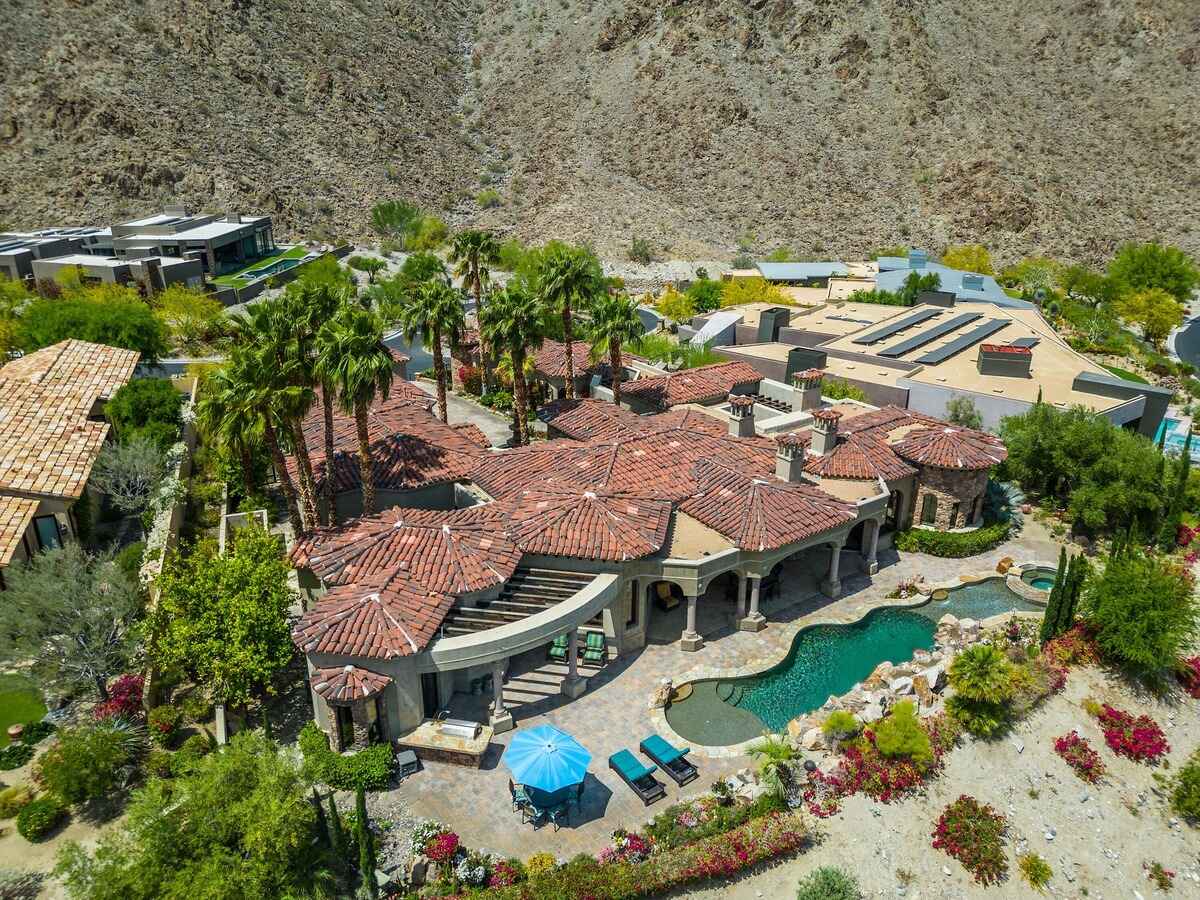 Aerial view of Mediterranean-style villa with tiled roof, pool, and surrounding desert landscape.