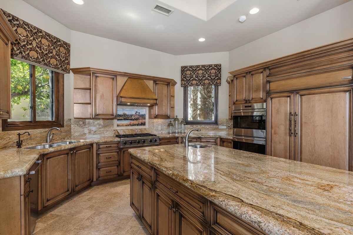 Close-up of kitchen showcasing stainless steel appliances, large windows, and detailed cabinetry.