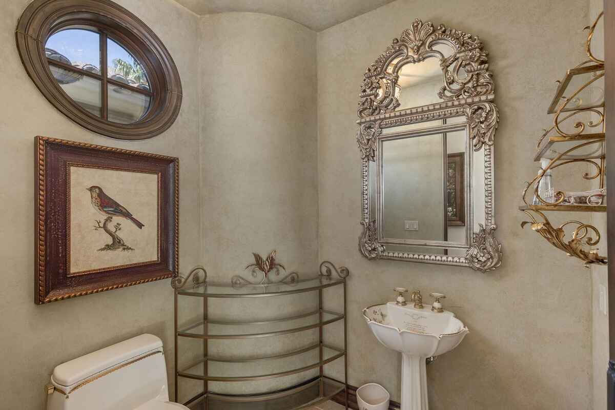 Powder room featuring a decorative mirror, pedestal sink, and circular window. 