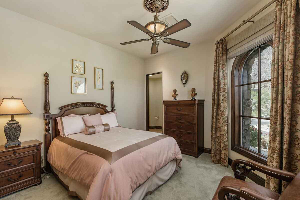 Bedroom with a four-poster bed, classic furnishings, and an arched window offering outdoor views.