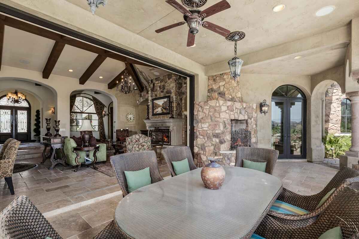 Outdoor patio area with a dining table, wicker chairs, and views of the interior and exterior spaces.