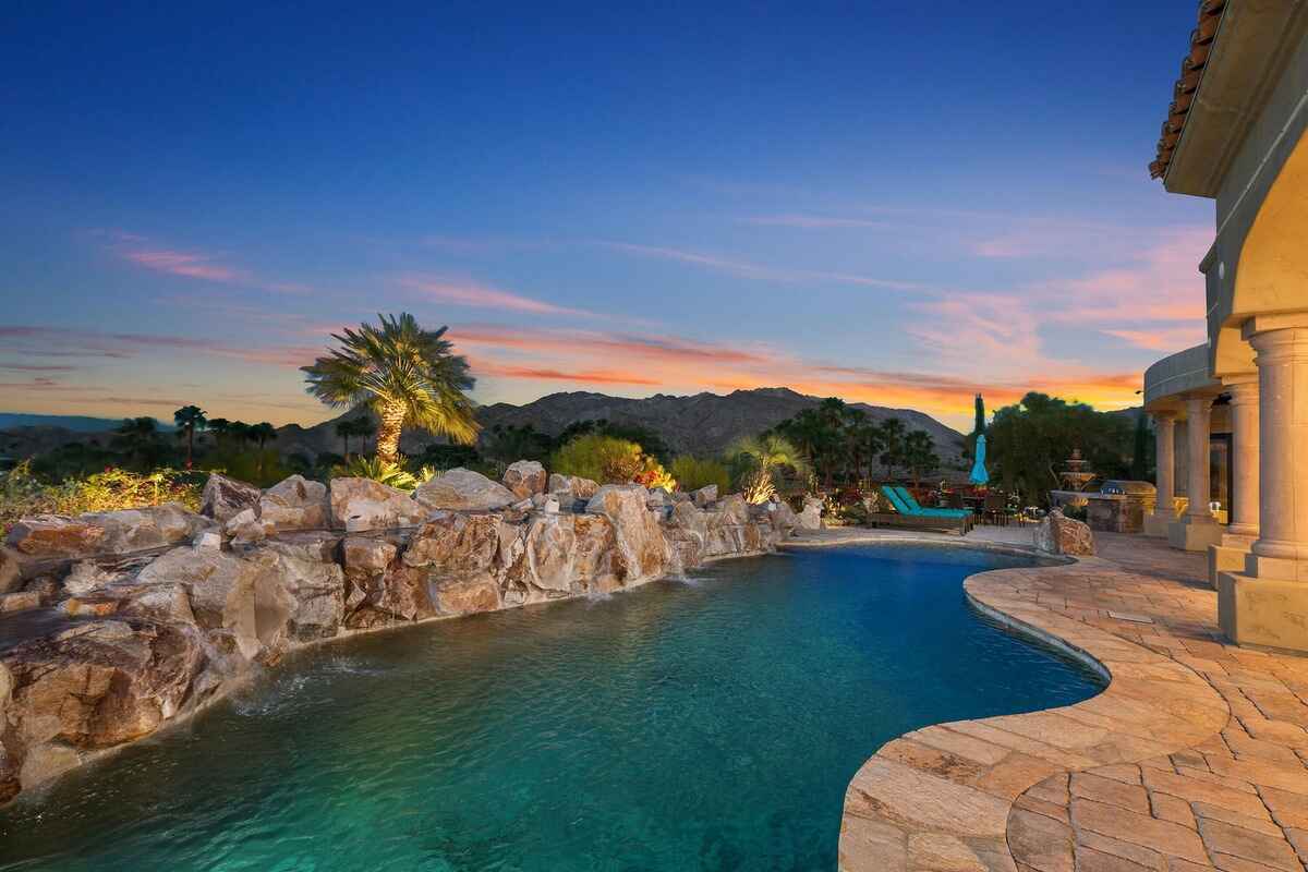 Sparkling pool with natural rock accents and a scenic view of the surrounding hills at sunset.