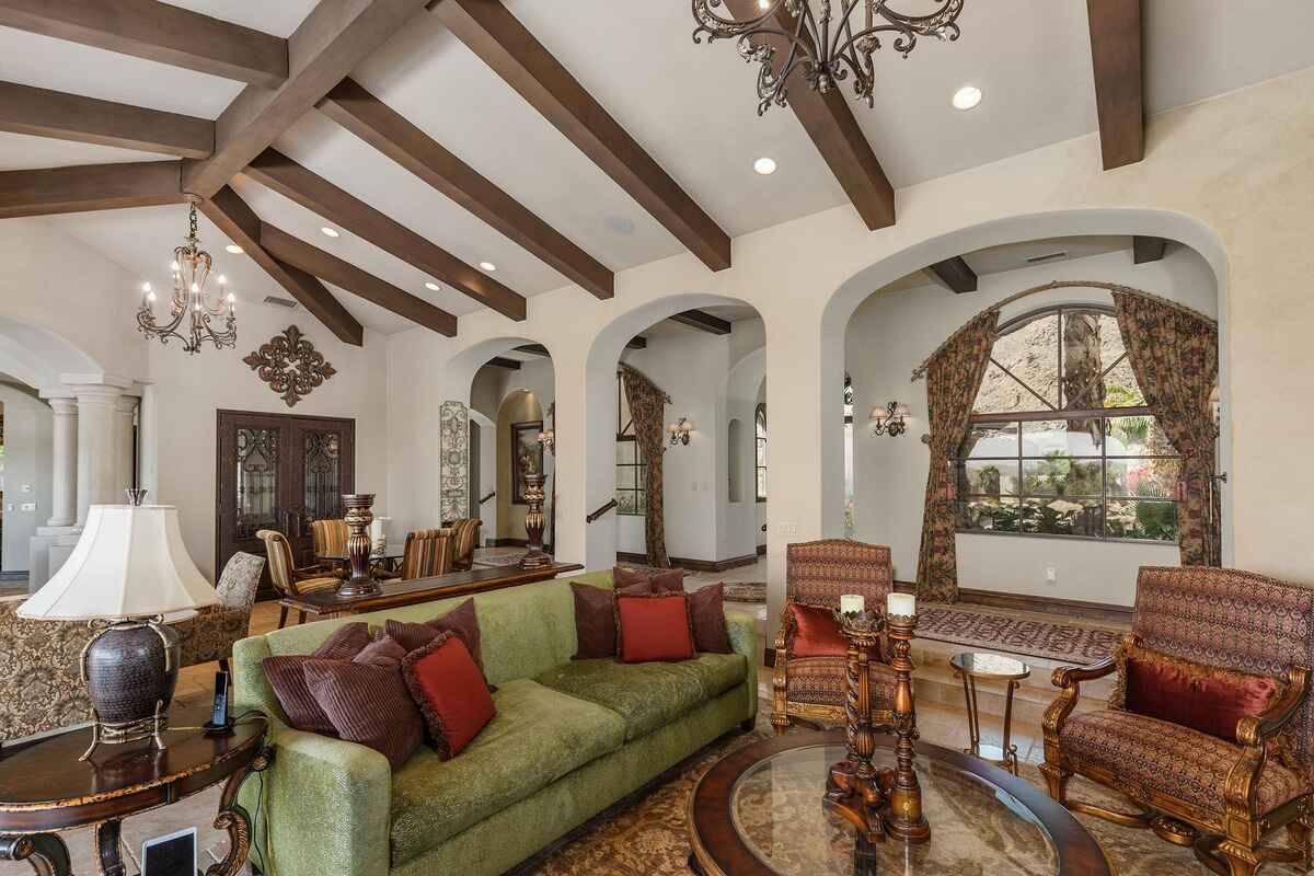 Spacious living area with arched windows, patterned curtains, and traditional furnishings.