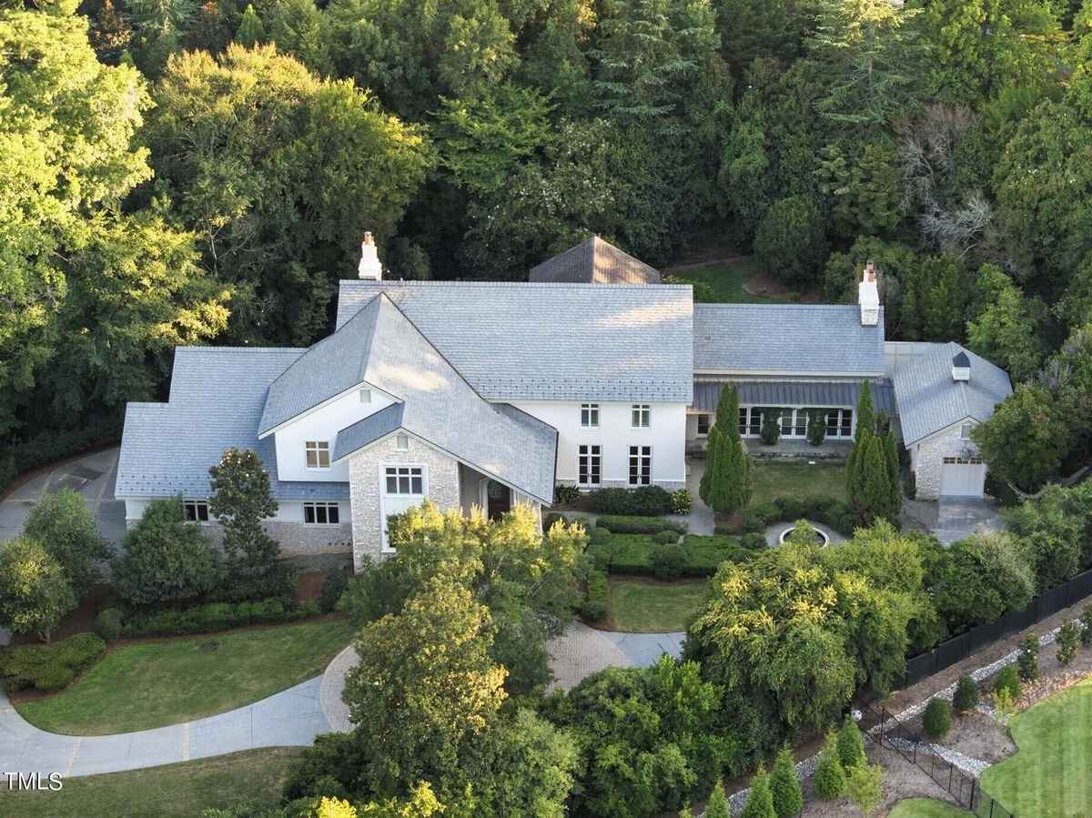 Aerial view showcasing the grandeur of a large estate surrounded by lush greenery.