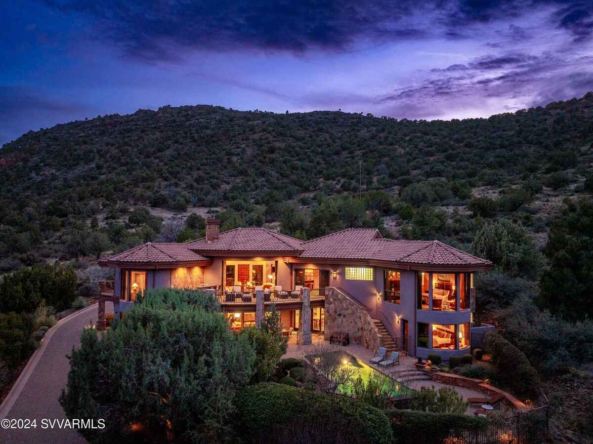 Night view of the house, illuminated to show outdoor and indoor spaces with surrounding hills.