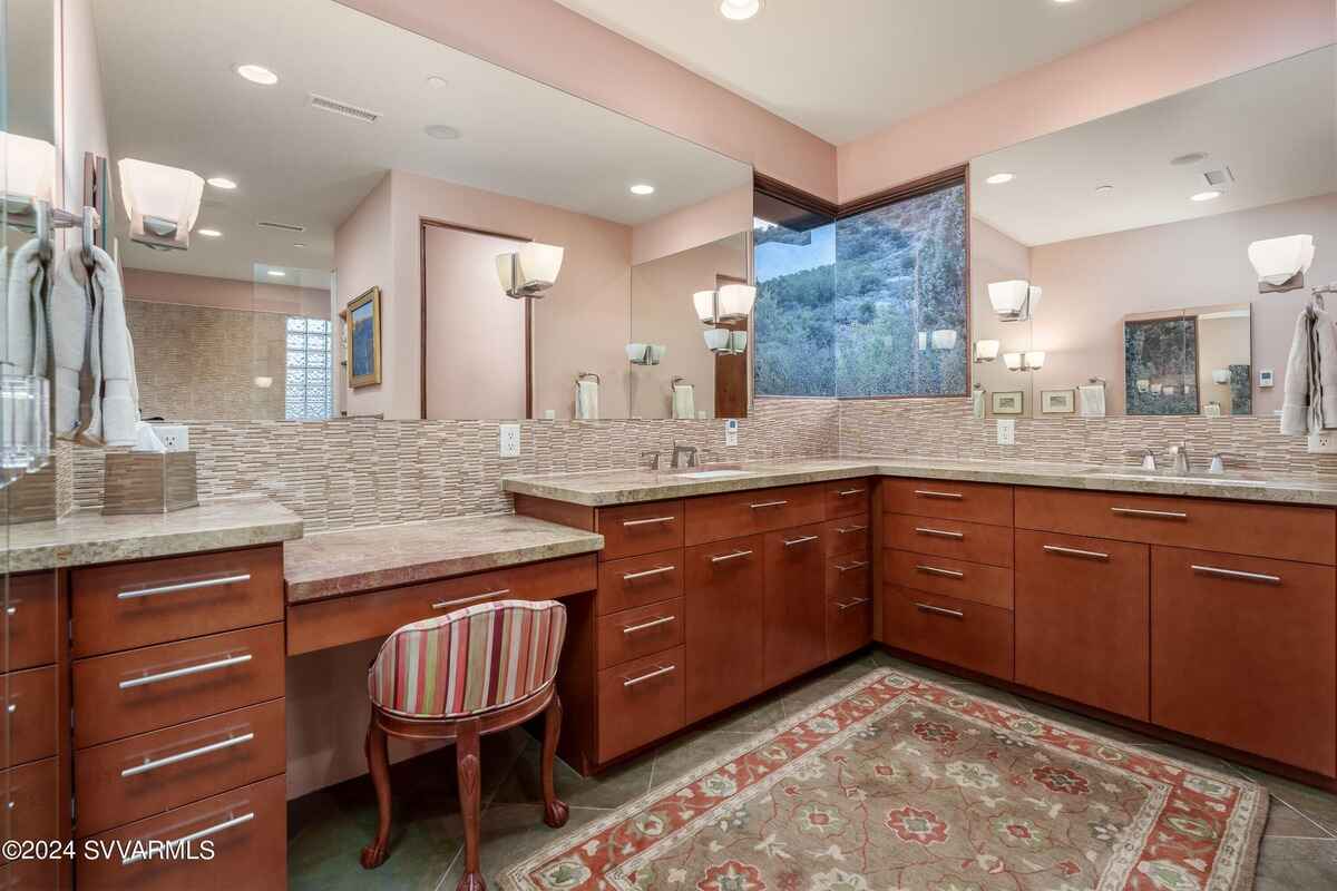 A spacious bathroom with dual sinks, a large mirror, and ample storage.