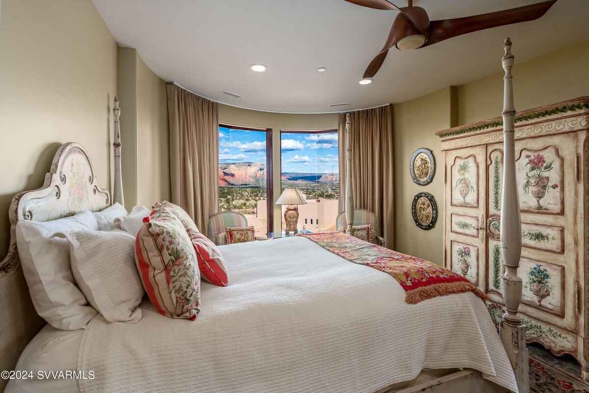 A bedroom with a serene view of red rock formations through expansive windows.