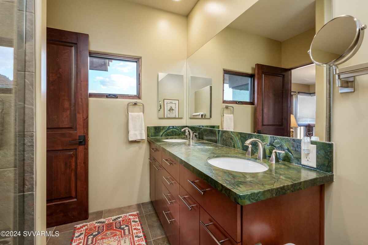 Bathroom featuring dual sinks, a green marble countertop, and a large mirror.