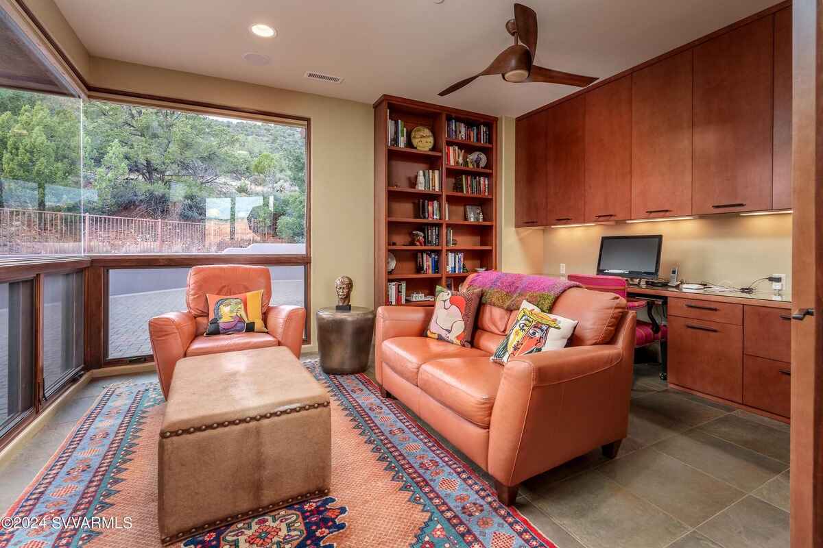 Home office with built-in bookshelves, a desk, and a cozy seating area near a large window.