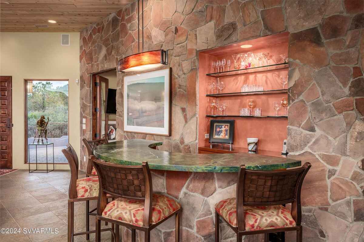 A bar area with stone walls and a curved countertop, offering a cozy entertaining space.