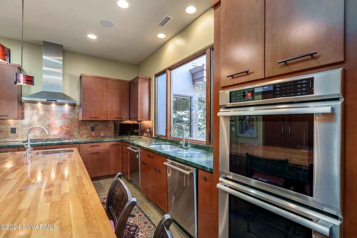 Close-up of a modern kitchen setup with stainless steel appliances and a view of an adjacent courtyard.