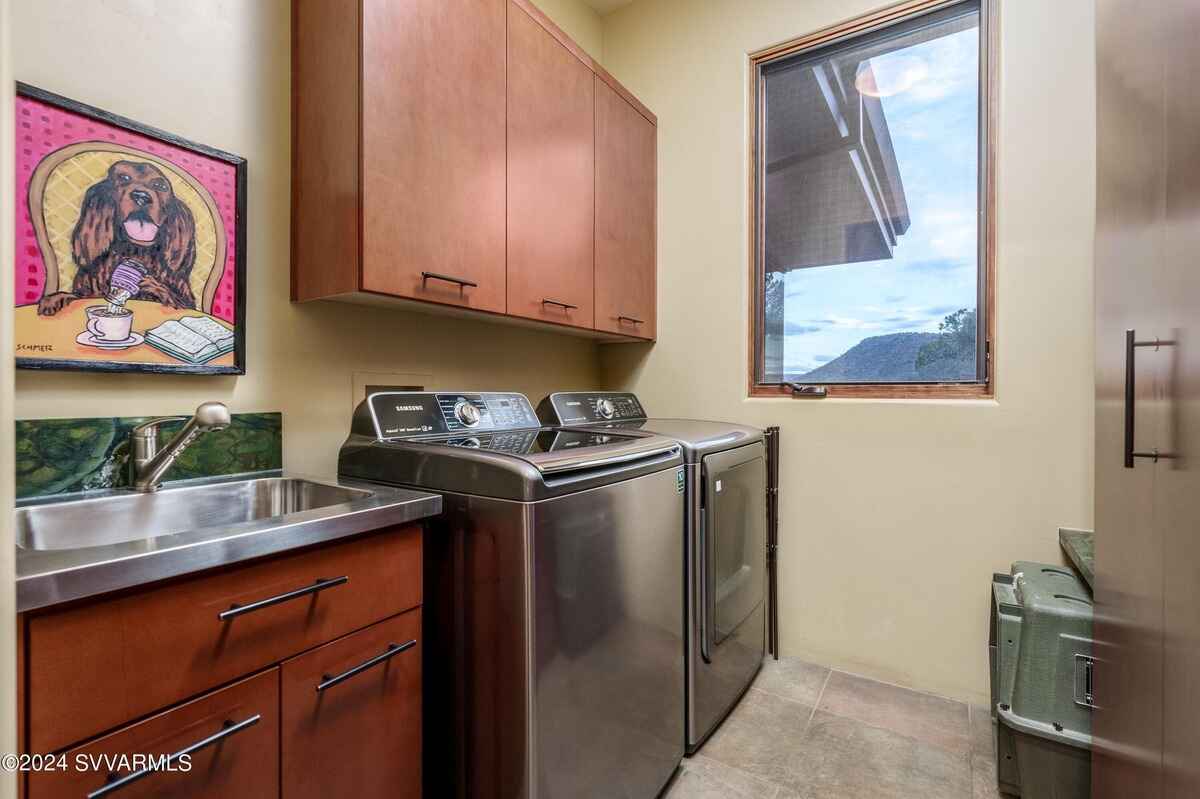 Laundry room with stainless steel washer, dryer, and sink, featuring a window with a view.