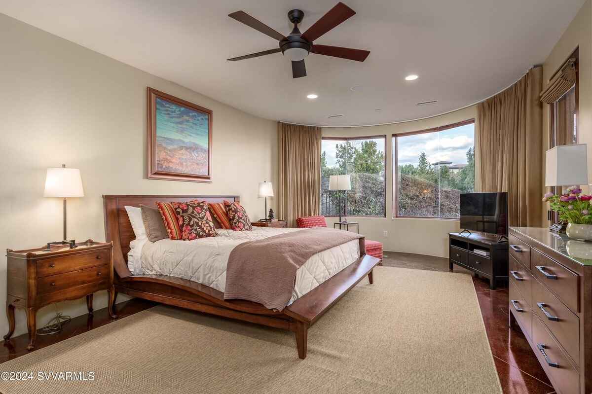 A bedroom with a curved window wall showcasing outdoor greenery and a relaxed setting.