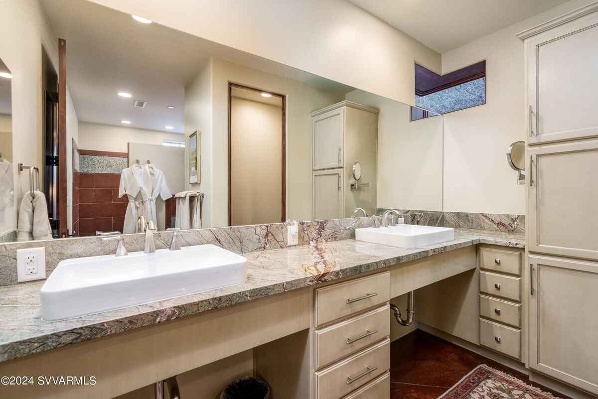 Bathroom with a marble countertop and dual sinks, offering modern design and ample storage.