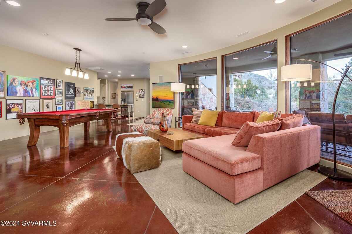 Recreation room with a pool table, large sectional sofa, and wall-mounted art and posters.