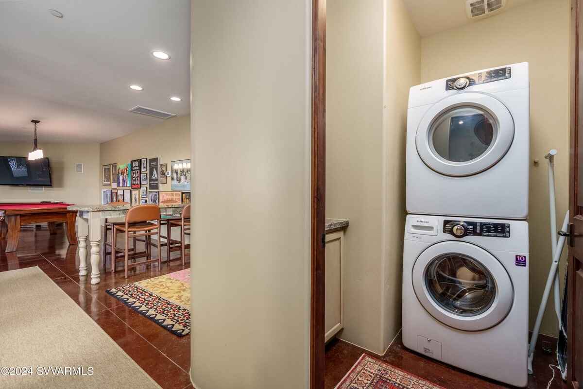 Compact laundry area with a stacked washer and dryer, adjacent to a recreation space.