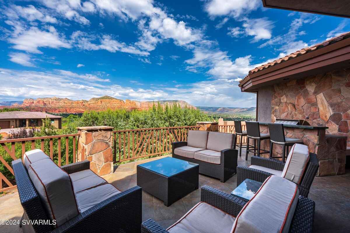 Outdoor patio with seating and a bar area, overlooking a scenic desert landscape.