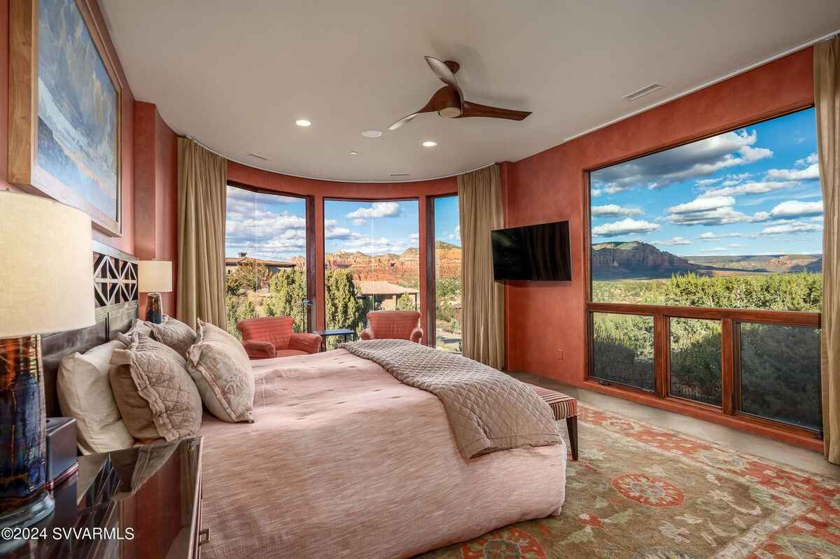 A bedroom with large windows offering stunning views of red rock formations.