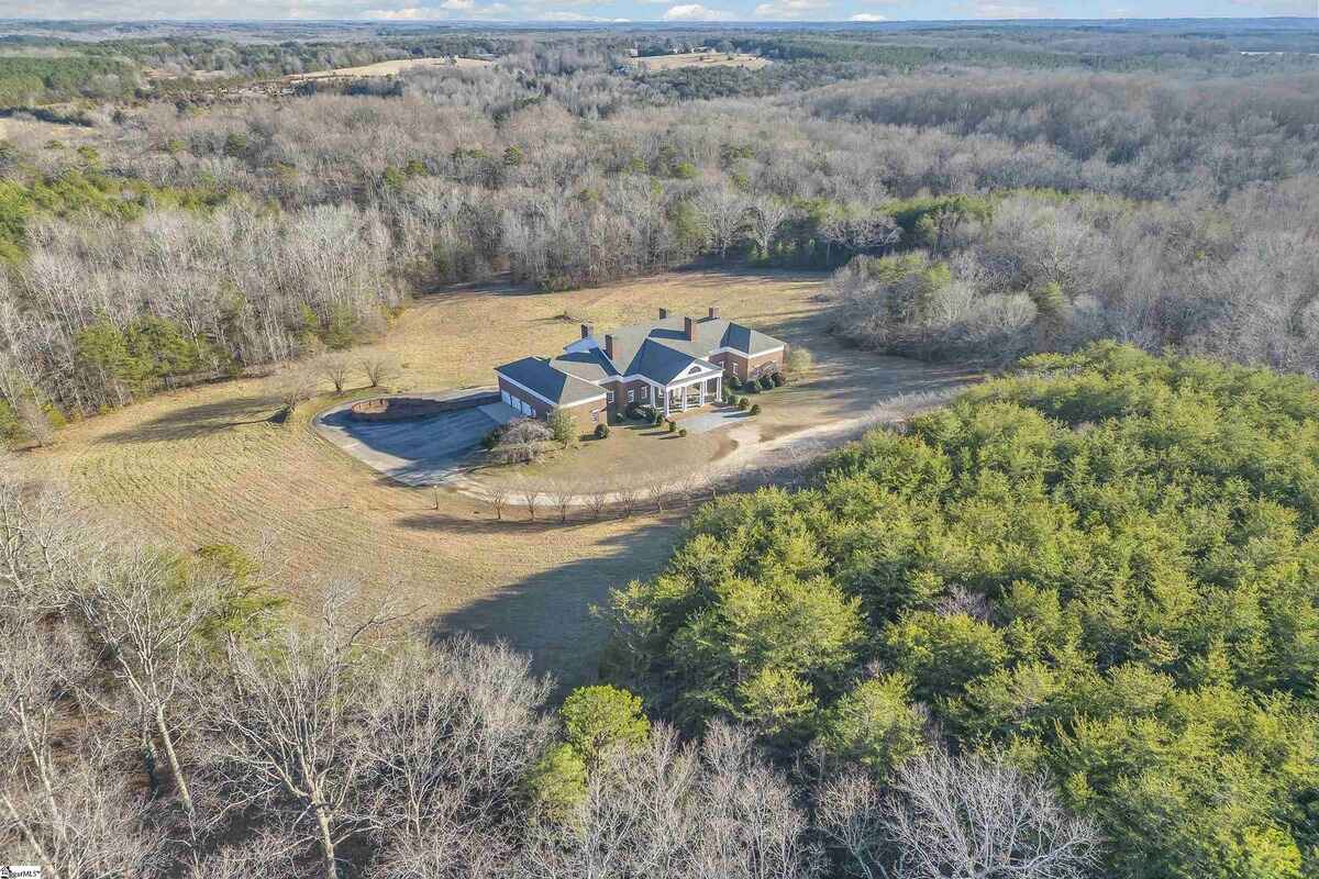 Grand brick estate surrounded by vast greenery and natural landscapes.