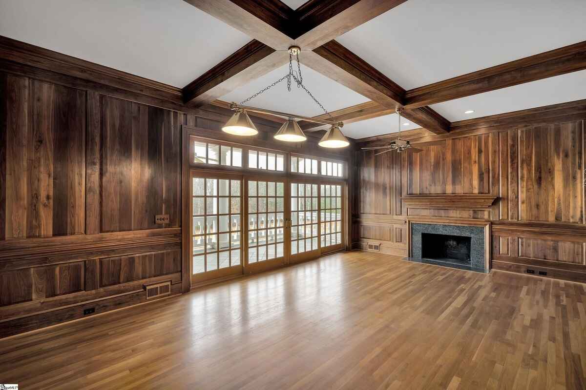 Wood-paneled room with coffered ceilings, large windows, and a fireplace.