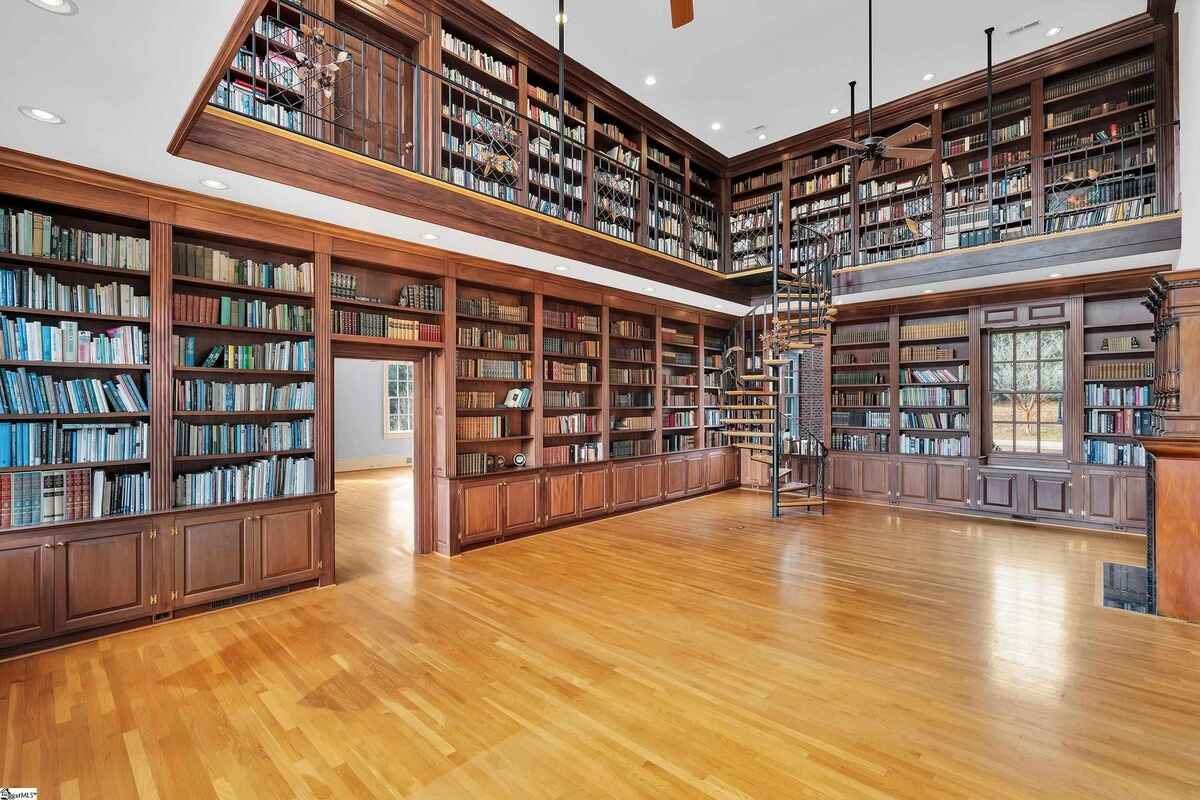 Expansive library space with bookshelves lining both floors and warm natural light.