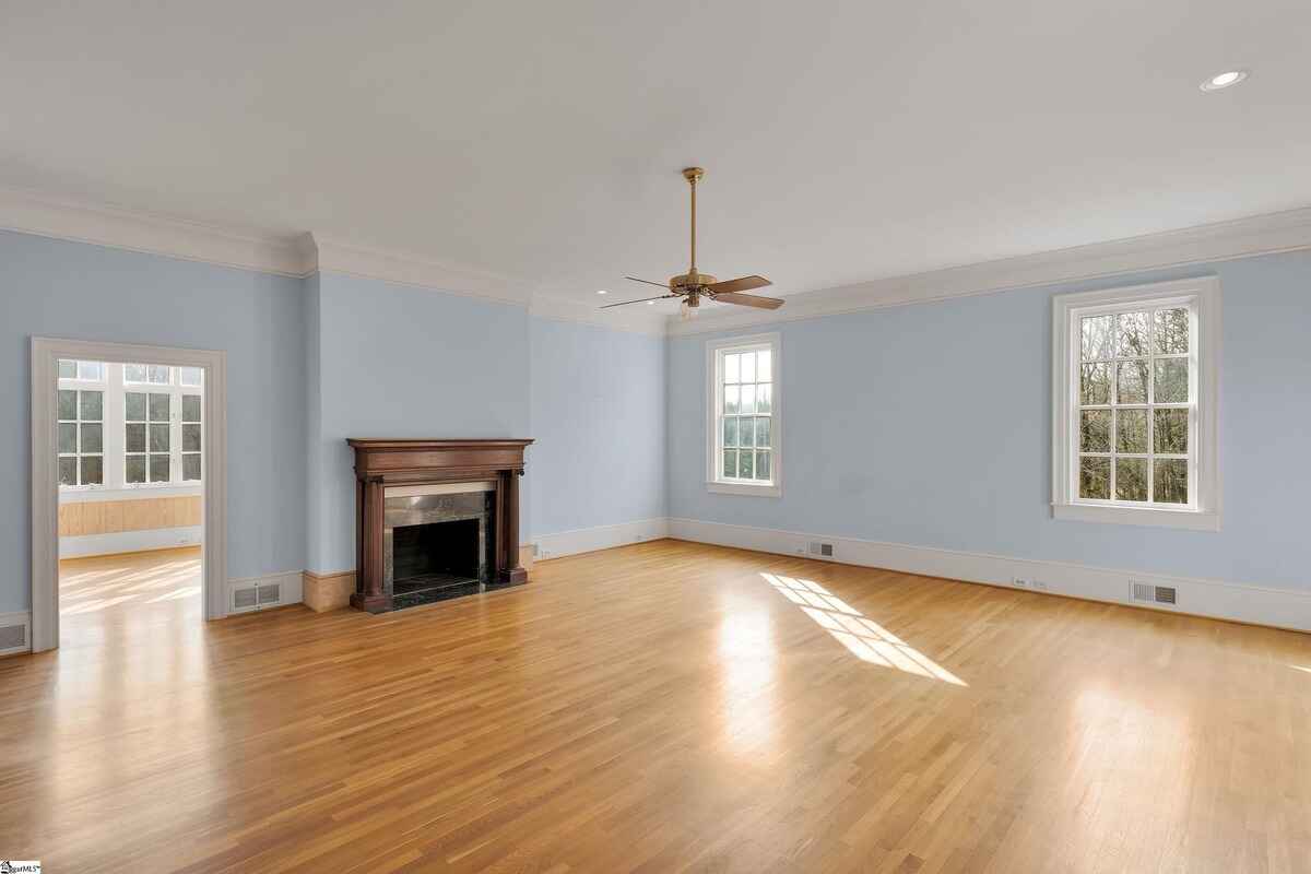 Spacious room with light blue walls, a fireplace, and hardwood floors.