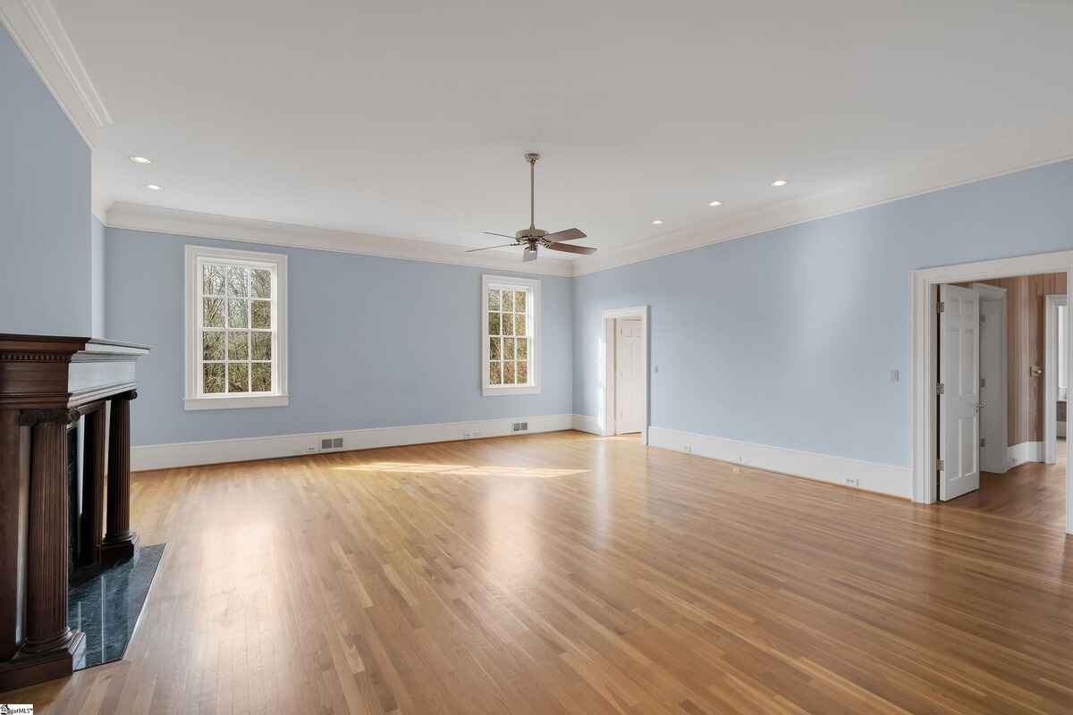 Bright room with windows along one side, light blue walls, and a central ceiling fan.