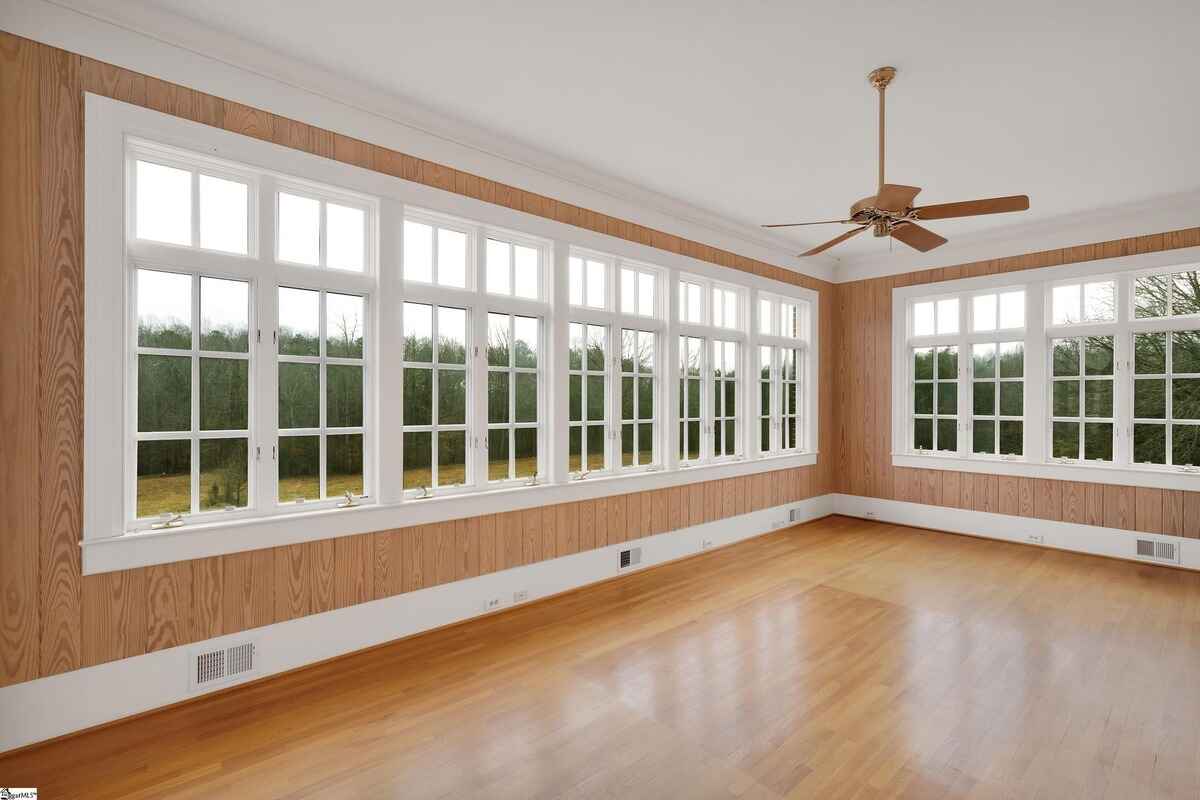 Sunroom with floor-to-ceiling windows offering views of greenery and natural light.