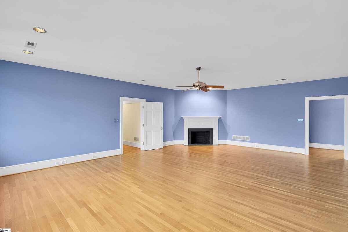 Large room with soft blue walls, a fireplace, and ample floor space for flexible use.