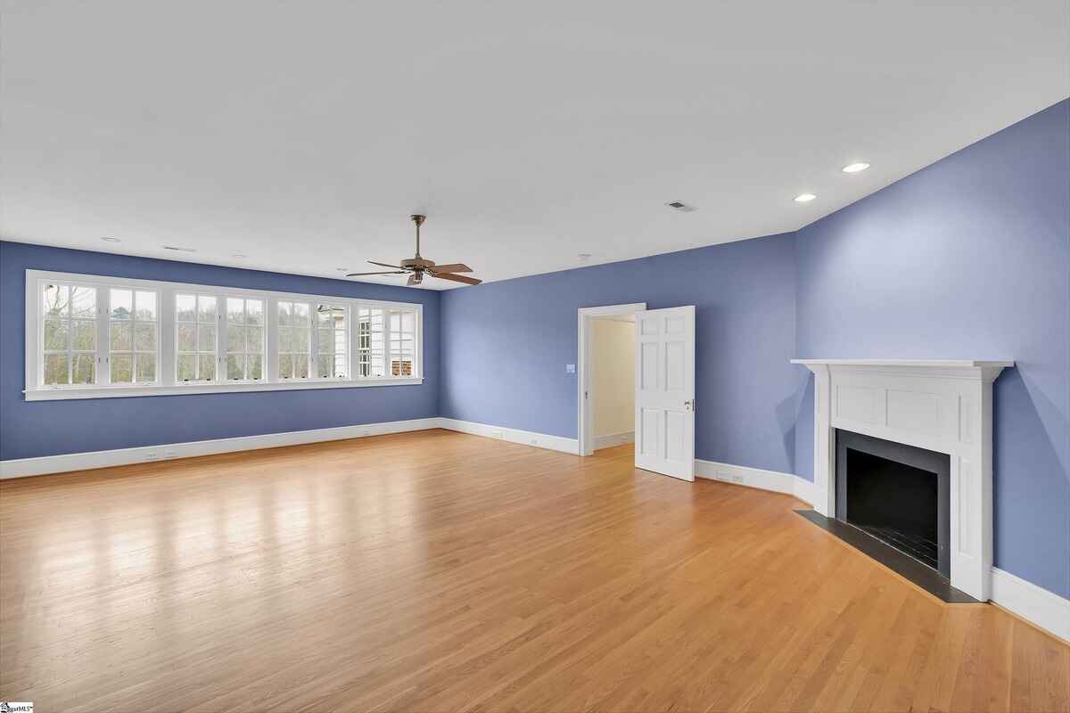 Large room with windows along one wall, hardwood flooring, and blue walls.