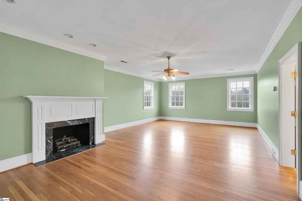 Fireplace in the corner of a large green bedroom with multiple windows.