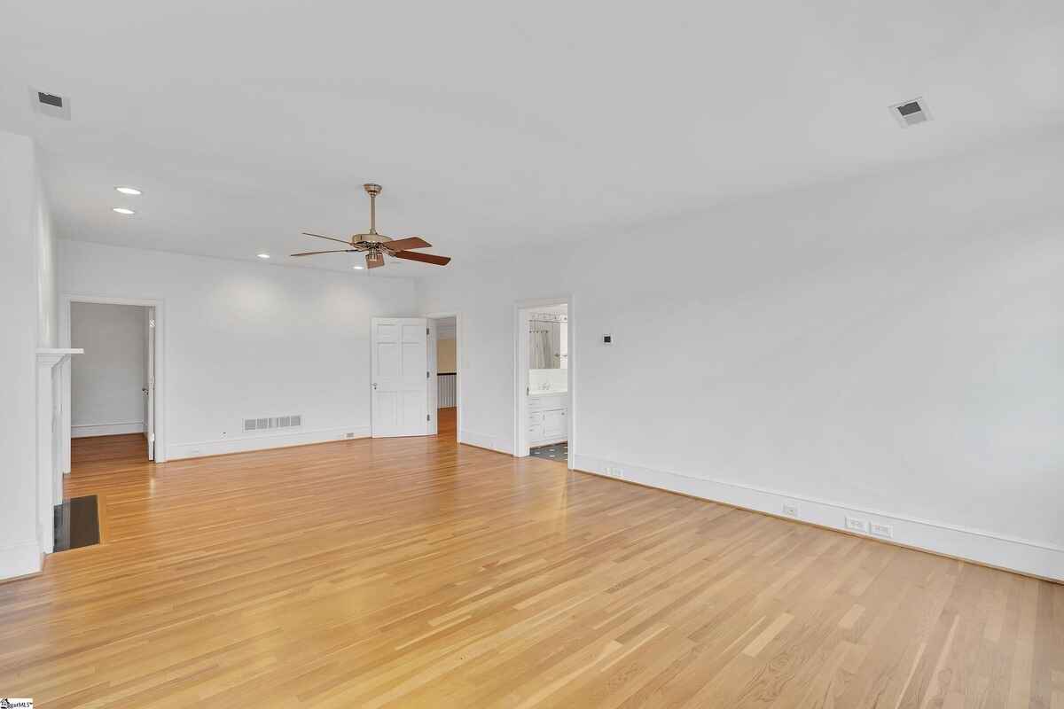 Open white-painted bedroom featuring a ceiling fan and hardwood floors.