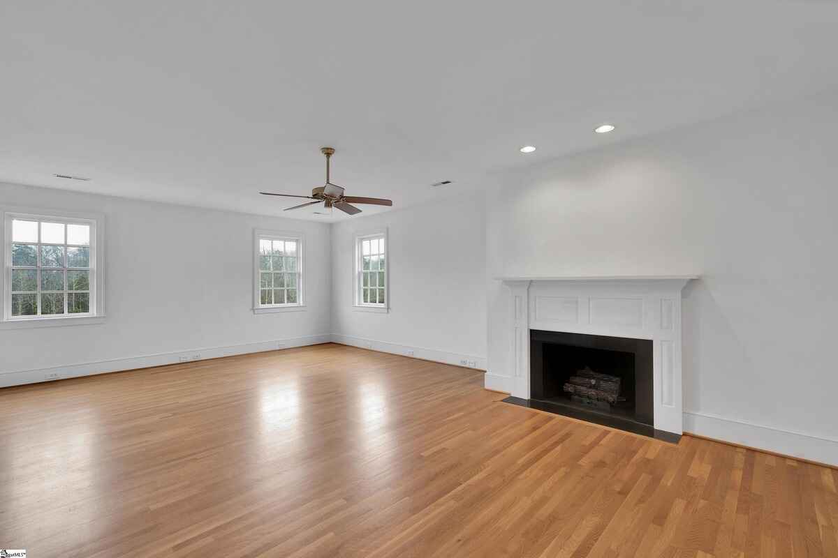 White bedroom with a centered fireplace and natural light through windows.