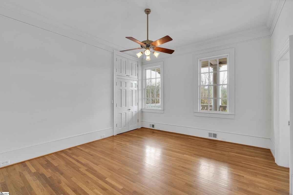 Bright bedroom with hardwood floors, ceiling fan, and access to a small closet.