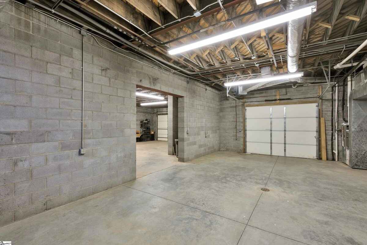 Basement garage area with cinderblock walls, exposed ceiling, and concrete flooring.