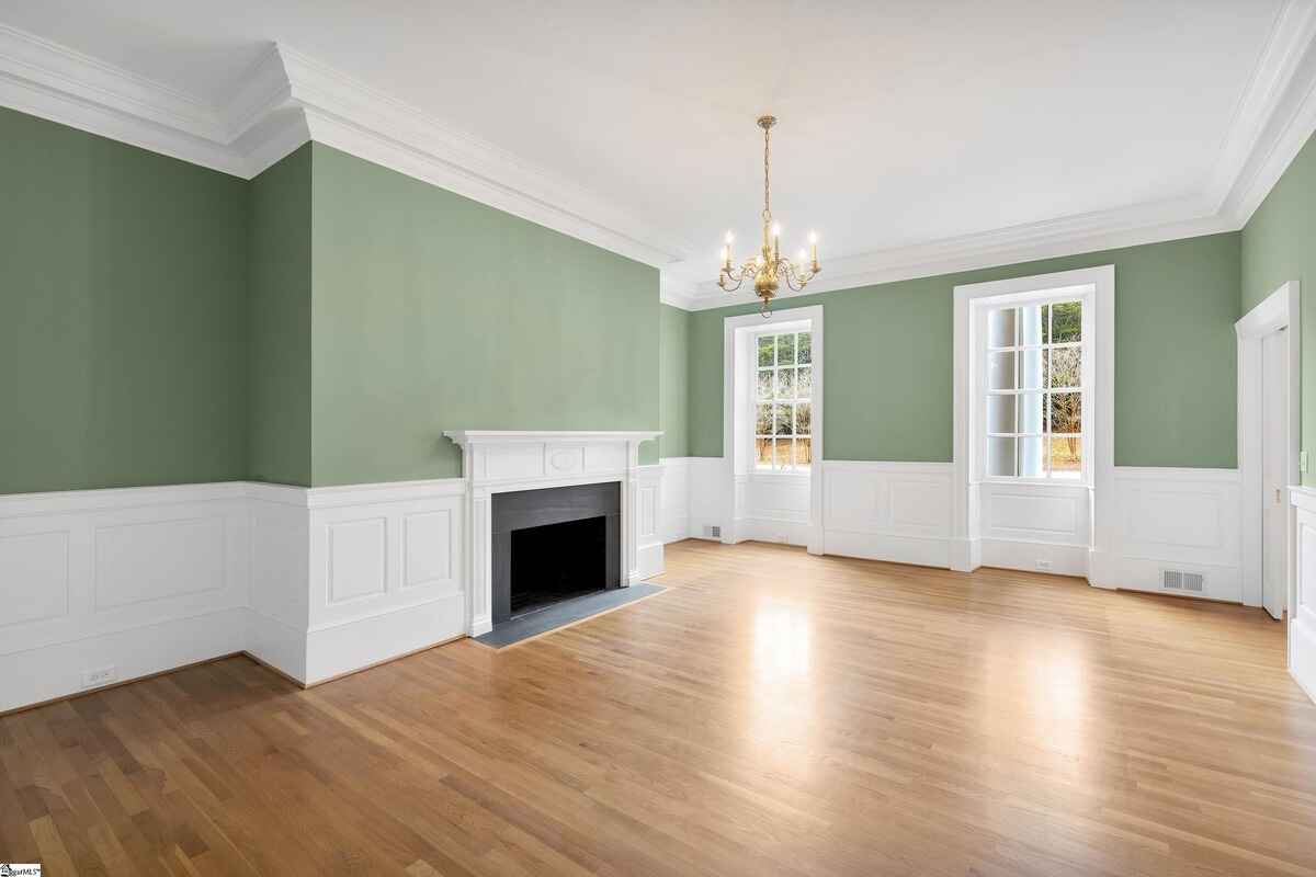 Refined sitting room with green walls, white wainscoting, and a fireplace.