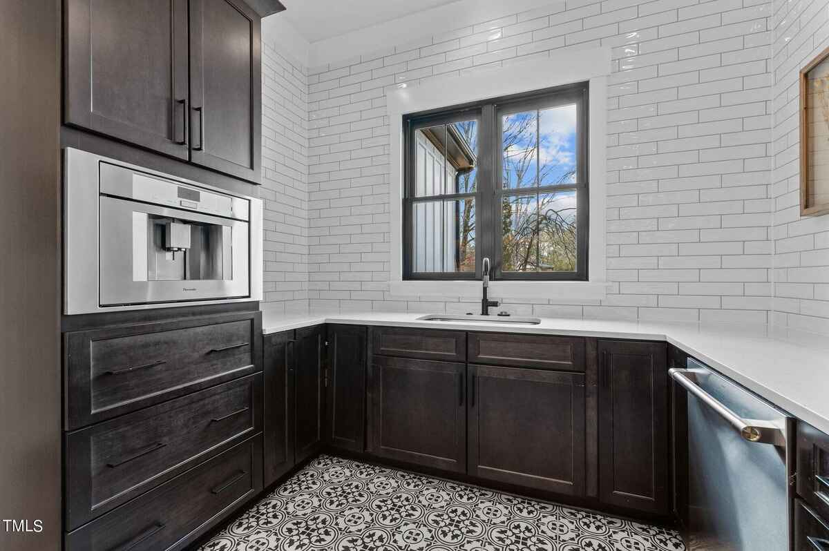 Compact beverage station with built-in coffee maker, dark cabinets, and white subway tile backsplash.