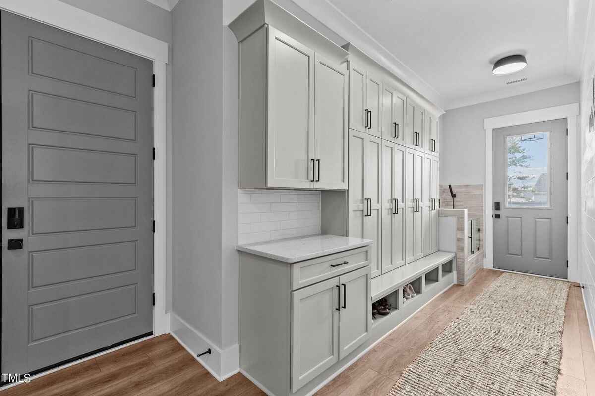 Mudroom with built-in storage, coat hooks, and a gray door.